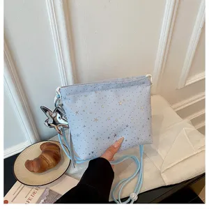 Close-up detail of light blue crossbody bag with gold star prints and star pendant.