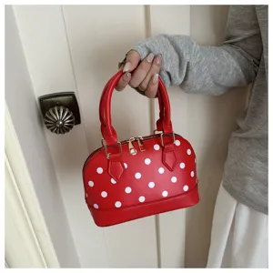Close-up detail of the red and white polka dot dome handbag showing metal zipper and handle.