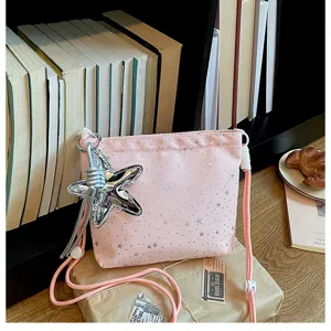 Pink canvas crossbody bag with silver star print, star charm and drawstring, detail view.