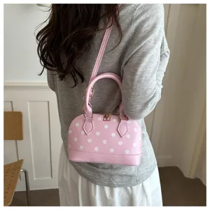 Pink polka dot dome handbag detail, stylish shoulder bag with top handle and strap.