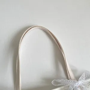 Nahaufnahme der stilvollen Canvas-Taschen-Griffe mit süßer weißer Spitzen-Schleife-Deko.
