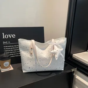 Detailansicht der weißen Segeltuchtasche mit Sternenmuster und niedlichem Anhänger.