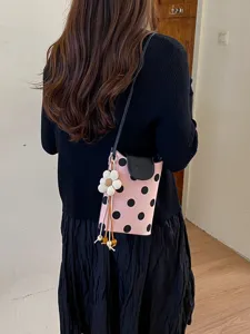 Sac bandoulière chic à pois roses pour femmes avec rabat noir et joli pendentif fleur.