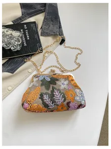 Primo piano del ricamo floreale e paillettes sulla borsa da sera chic con chiusura in metallo.
