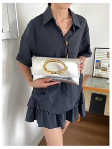 Zilveren metallische enveloppe clutch tas met gouden handvat voor stijlvolle dames.