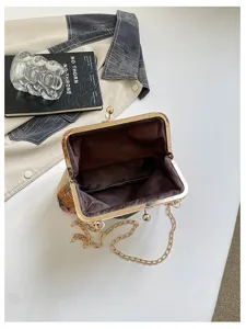 Dettaglio della borsa a tracolla, elegante borsa da sera ricamata con catena metallica.