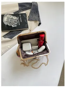 Dettaglio in primo piano dell'elegante pochette da sera con ricamo floreale e catena dorata.
