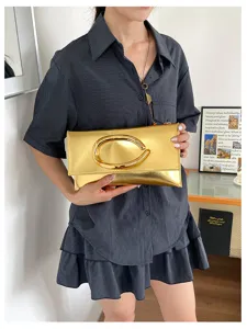 Gouden metallische envelope clutch tas detail met unieke C-vormige metalen gesp.