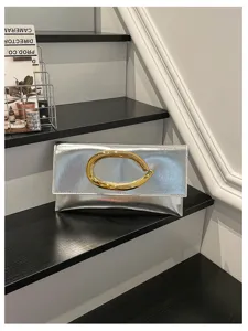 Gedetailleerd overzicht van zilveren enveloppe clutch tas met opvallende gouden C-handgreep.