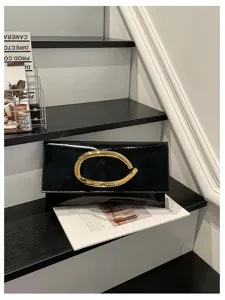Detailopname van de zwarte lakleder envelop clutch met gouden metalen ring op de trap