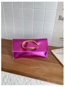 Stijlvolle metallic roze envelop clutch tas met uniek gouden sculpturale handvat voor dames.