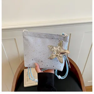 Detail shot of light blue star pattern crossbody bag with metallic star charm and drawstrings.