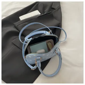 Chic light blue polka dot shell bag with top handle and crossbody strap, stylish daily purse.