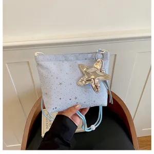 Close-up of light blue crossbody bucket bag with silver star prints and big star pendant.