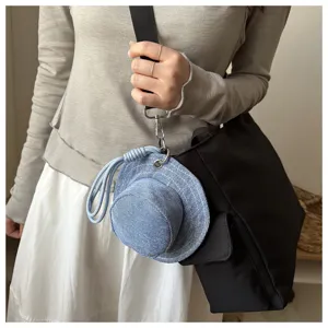 Denim fisherman hat shaped coin purse pendant attached to black bag strap, creative accessory.