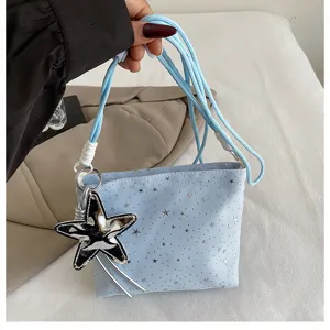 Closeup detail of the light blue crossbody bag with silver stars and stylish star pendant.