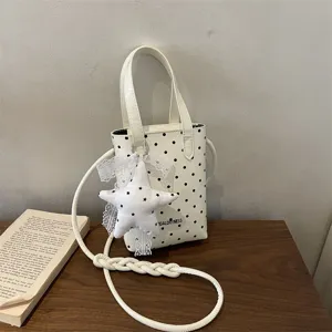 Bolso pequeno blanco de lunares con colgante de estrella y correa trenzada elegante.