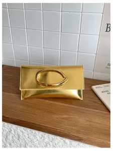 Detailweergave van de metallic gouden envelop clutch tas met een chique C-vormige metalen greep.