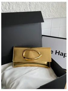 Metallic goudkleurige enveloppe clutch tas met unieke C-vormige metalen gesp detail.