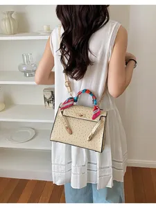 Stylish women shoulder handbag with elegant ostrich pattern texture and chic handle twilly scarf.