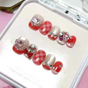 Vista detallada de uñas postizas hechas a mano con efecto cat-eye, pedrería y lazos.