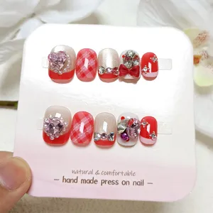 Detalle de uñas postizas hechas a mano con exquisitos cristales de corazón y diseño de cuadros.