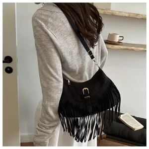 Close-up detail of a vintage black suede fringe shoulder bag worn by a model indoors.