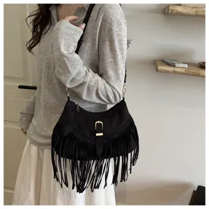 Detail view of the black suede fringe shoulder bag featuring delicate golden hardware.