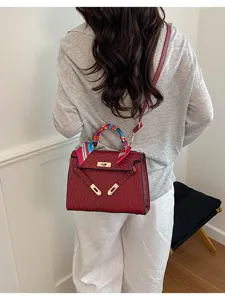 Detail view of the elegant red ostrich textured shoulder bag with chic twilly scarf accent.