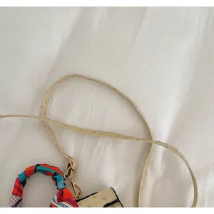 Close-up detail of women fashion handbag strap and twilly scarf decoration on white background.