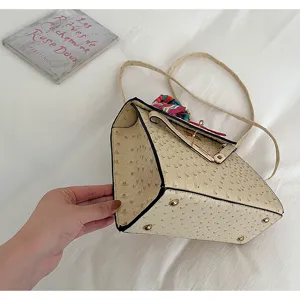 Close-up detail of beige ostrich leather handbag with turn lock and silk scarf decoration.