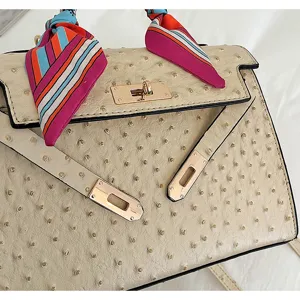 Close-up of women ostrich pattern handbag with gold hardware and colorful silk scarf detail.