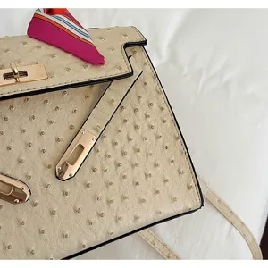 Detail shot of women luxury retro ostrich pattern handbag with metal lock and chic twilly scarf.