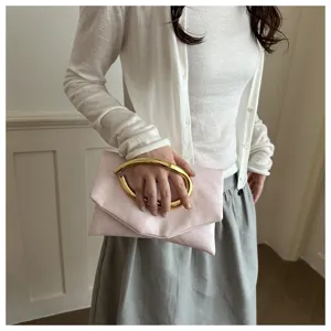 Detail shot of a stylish pink clutch bag featuring a striking gold metal ring handle.
