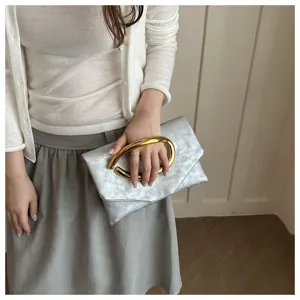 Stylish silver clutch bag for women with unique gold ring handle, elegant evening fashion purse.