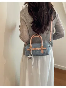 Denim shoulder bag back view detail showcasing pink leather strap and star charm accessory.