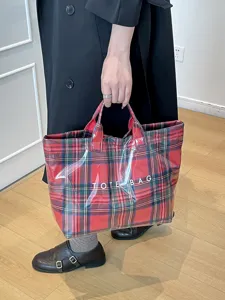 Waterproof plaid tote bag close up detail view showing durable texture and classic red tartan pattern.