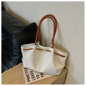 Minimalist white hobo shoulder bag detail featuring contrast brown handles and drawstring.