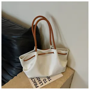 Detail shot of the white hobo shoulder bag featuring stylish brown handles and secure drawstring.