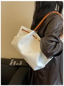 Close-up detail of white hobo shoulder bag with brown straps and drawstring closure scene.