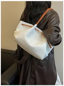 Detail shot of a stylish white hobo shoulder bag with brown leather straps and drawstring.