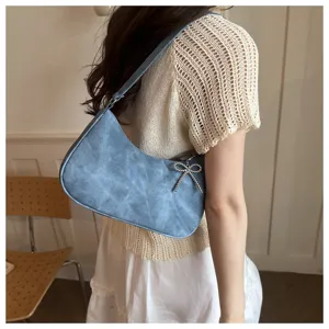 Blue denim texture underarm shoulder bag with sparkling rhinestone bow for daily commuting.