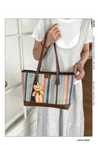 Stylish color-block woven tote bag with cute bear pendant and brown leather details detail.