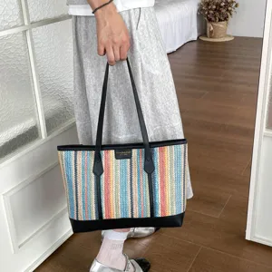 Detailed view of colorful striped straw beach bag with leather handles and chic design.