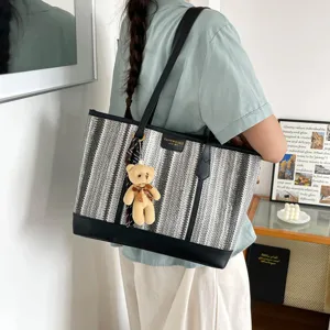 Stylish straw woven tote bag with contrast stripes, leather trim, and cute teddy bear pendant.