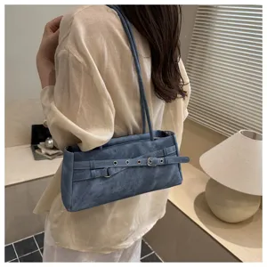 Close-up detail of the stylish blue denim shoulder bag featuring unique belt and metal buckle.