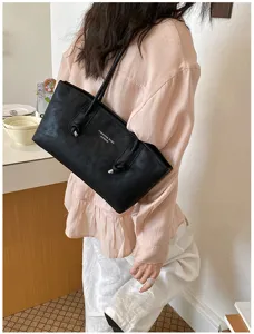 Detailed view of the black minimalist shoulder tote bag showing its sleek texture and stylish strap design.