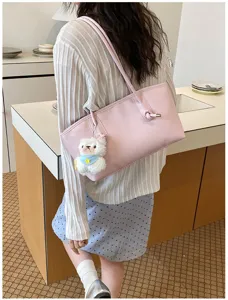 Detailed view of the vintage solid color leather tote shoulder bag with a cute bear pendant.