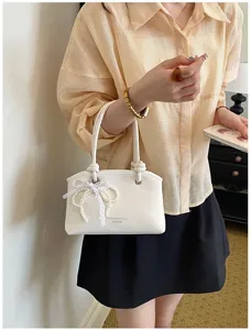 Nahaufnahme einer eleganten weißen Schultertasche mit Perlen-Spitzen-Schleife für Damen.