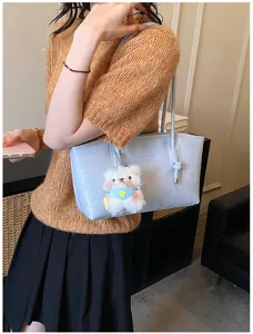 Stylish light blue tote shoulder bag with cute plush bear pendant, perfect daily wear.